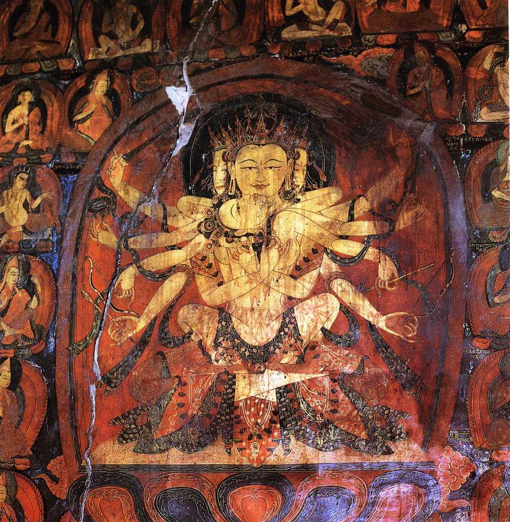 Tibet Guge 08 Tsaparang 03 Yamantaka Temple Guhysamaja-Manjuvajra On the left wall in yab-yum with his consort Sparshavajra are three paintings of the three-faced six-armed Guhyasamaja, Guhyasamaja-Manjuvajra and Guhyasamaja-Akshobyavajra, associated with the Buddha Akshobhya, and the most ancient and fundamental Tantra of Vajrayana tradition of Buddhism. Here is Guhyasamaja-Manjuvajra with his two central hands crossed near the centre of his body, his right hands holding a sword and arrow, and his left holding a lotus and bow. Sparshavajras two main hands circle Guhyasamaja- Manjuvajra, while her other hands mirror his. Photo: Weyer/Aschoff: Tsaparang, Tibets Grosses Geheimnis